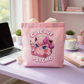 Pink "Cute But Psycho" tote bag by Printify featuring bold black text and a kawaii style, shown hanging with handles visible.