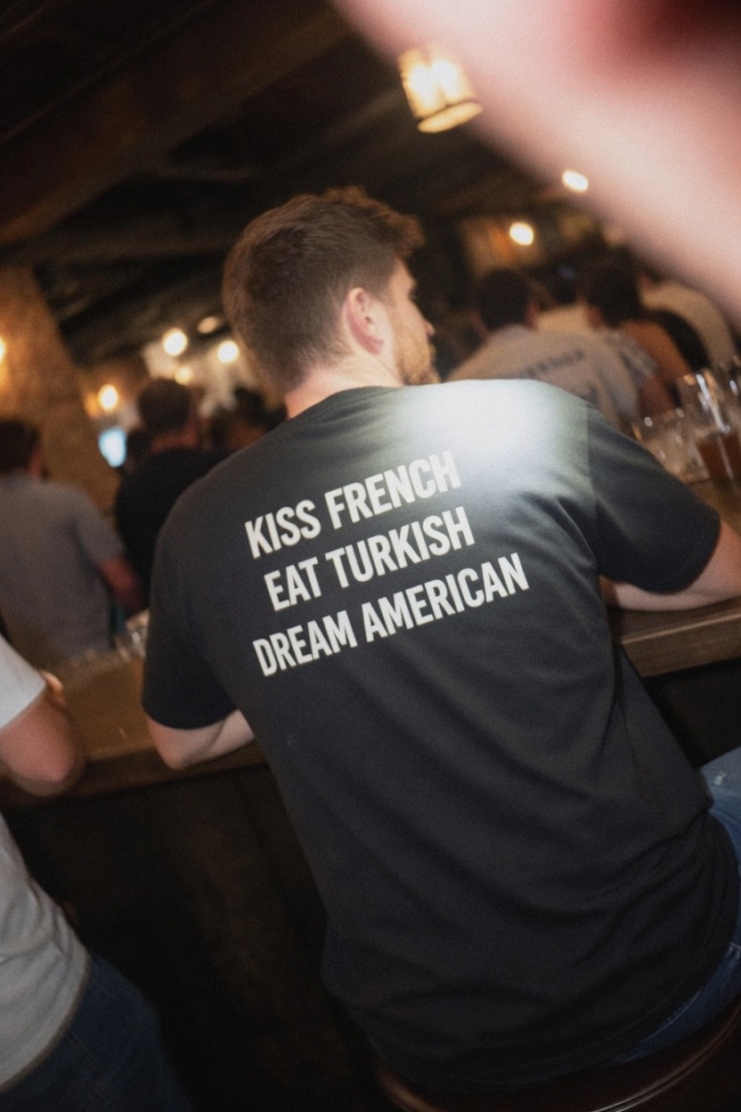 Unisex cotton T-shirt featuring "Kiss French, Eat Turkish, Dream American" print, ideal for international couples.